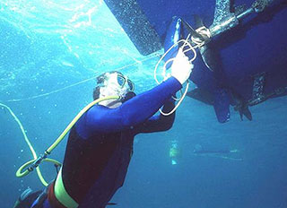 A diver using a dive hookah to clear a rope tangled in a boat propeller Picture