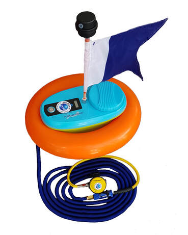 A small compact oval shaped mini hookah diving system with the diver flag on top of the oval shaped blue container for the hookah compressor battery housing. The housing is surrounded by the inflated floatation ring with a dark blue hookah breathing air hose and yellow dive regulator coiled below Picture